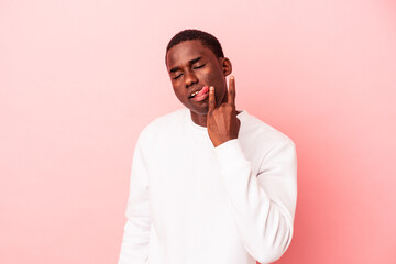 Young African American man isolated on pink background showing rock gesture with fingers