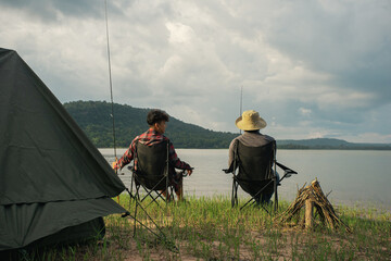 Friendship fisherman or Angler sitting a chair together and camping to fishing at the lake. Camping...