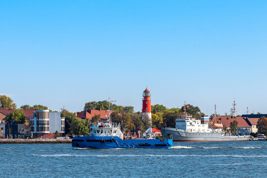Baltic lighthouse. Fishing vessel in the strait. Kaliningrad region. Baltiysk