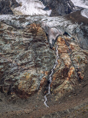 Minimalistic natural background of the glacier surface flowing stream. Minimal natural background of the ice wall. Beautiful natural texture of a dark glacial wall with streams of water.