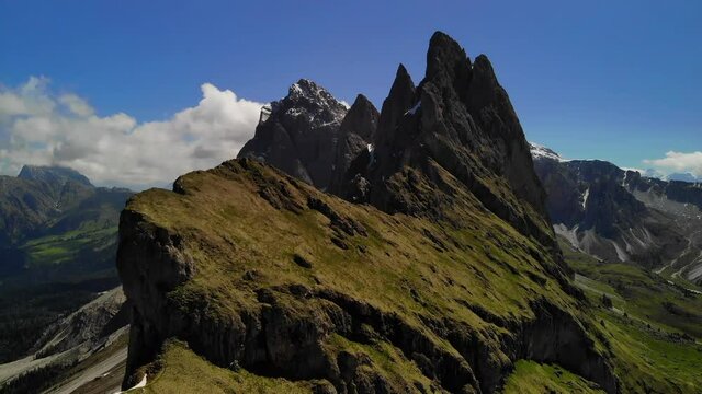 Seceda Ridgeline, Val Gardena, Dolomites, South Tyrol, Northern Italy.  Drone shot of the magnificent sharp peaks during a lush green, bright summers day, snow & ice valleys in the background.