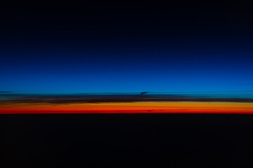 Abstract Sunset Photo from Airplane.  Deep blue sky with shining red-orange horizon.