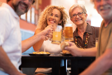 Happy cheerful family having fun and clinking beer glasses together while sitting at table in restaurant. Portrait of family toasting beer glasses and celebrating at restaurant