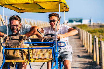 Mature man with teenage son riding cart on road during vacation. Father son enjoying leisure time...