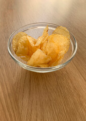 CHIPS IN A GLASS BOWL ON WOOD BACKGROUND