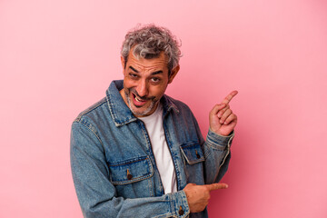 Middle age caucasian man isolated on pink background  pointing with forefingers to a copy space, expressing excitement and desire.