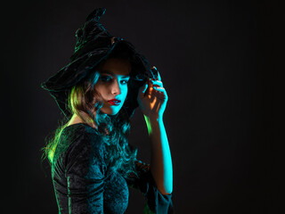 A witch creates magic, a young beautiful brunette in a pointed hat