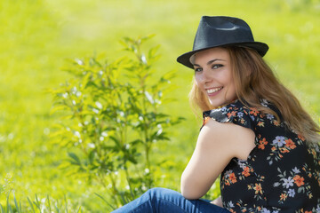 Laughing young girl is looking over her shoulder at the camera outdoors in summer day. Horizontally. 