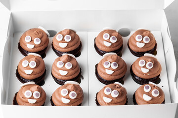 Set of cupcakes in the white gift box. Chocolate cupcake with brown cream cheese top decorated with mastic smiley face