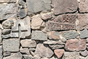 Armenia, Geghard, September 2021. The wall of the monastery of large stones with Christian ornament.