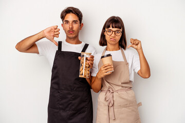 Young mixed race store clerk couple isolated on white background showing a dislike gesture, thumbs down. Disagreement concept.