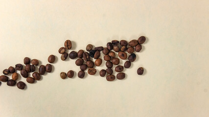 A few roasted coffee beans on a beige background.