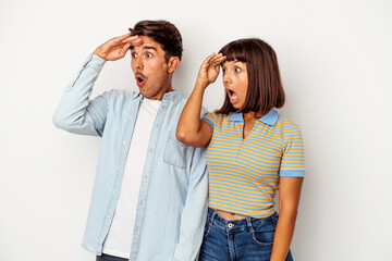 Young mixed race couple isolated on white background looking far away keeping hand on forehead.