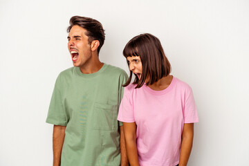 Fototapeta premium Young mixed race couple isolated on white background shouting very angry, rage concept, frustrated.