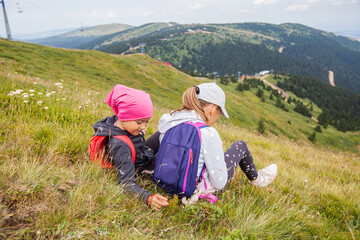 Fototapeta na wymiar Little girls hiker relaxing on the peak, beautiful view on nature landscape