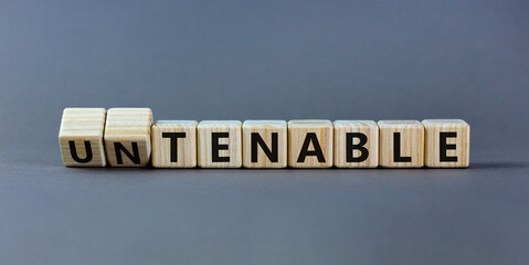 Tenable or untenable symbol. Turned wooden cubes and changed the word 'untenable' to 'tenable'. Beautiful grey table, grey background. Business, tenable or untenable concept, copy space.