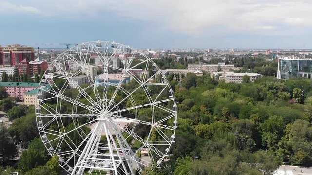 Big attraction is spinning. Ferris wheel in the city among the trees, drone shooting