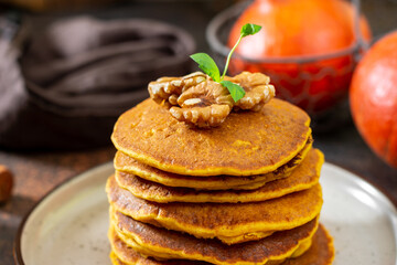 Pumpkin pancakes in a ceramic plate on a dark background close-up	