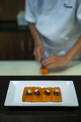 The chef prepares salmon sashimi. The process of making and decorating salmon sashimi. Salmon sashimi on white plate. Japanese traditional food.