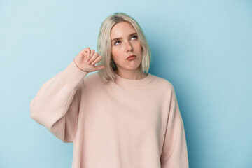 Young caucasian woman isolated on blue background showing a dislike gesture, thumbs down....