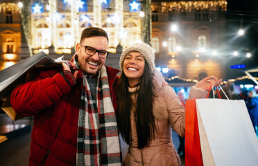 Obraz premium Portrait of happy couple shopping for Christmas in the city. People holiday happiness sale concept