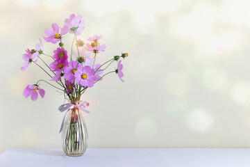 Simple background with pink field flowers in glass vase