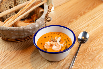 Tom yam soup and bread basket on a wooden table.
