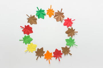 Simple background with autumn colorful maple origami folded paper leaves arranged in circle on white background