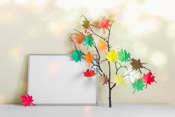 Mockup template with silver frame and branch with paper folded origami autumn maple leaves attached