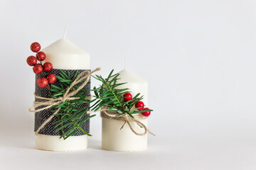 Christmas, New Year composition with two candles, evergreen branches and red berries on white background