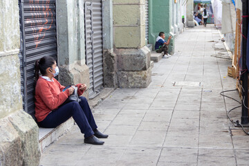 Mujer sentada afuera de pórtico de local.