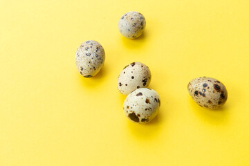 Several quail eggs on a yellow background.