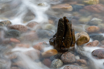 Holzgebilde von Wasser umspült am Strand