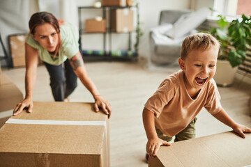 Portrait of two cheerful boys moving boxes while family relocating to new house, copy space