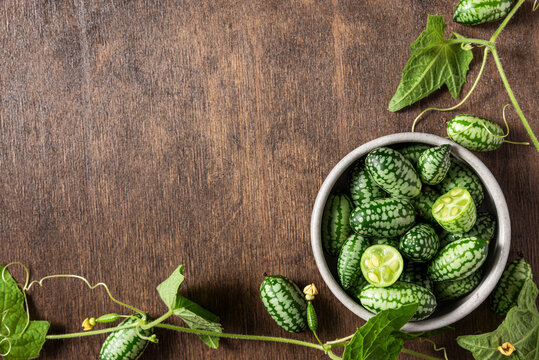 Cucamelon, Melothria scabra or mousemelon freshly harvested in a bowl with plant leaves on wooden background