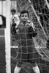 A boy football player near the gates of the stadium. Black and white photo.