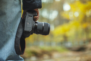 Fototapeta premium photo camera in hand over blurred forest background