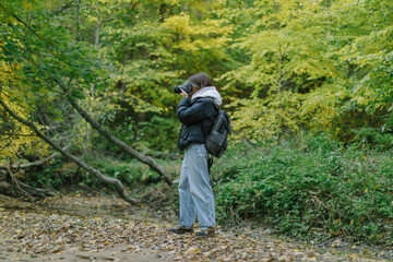 female photographer tourist taking photo in wild nature forest, side view