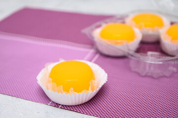 Close-up em um Quindim fora da embalagem plástica, sobremesa tradicional na culinária brasileira, feito com gemas de ovos, açúcar e coco ralado.	