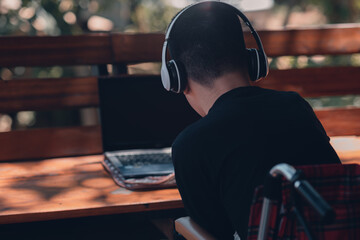 Asian teenager boy with disability on wheelchair using computer and listening music or video chat...