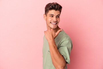 Obraz premium Young caucasian man isolated on pink background points with thumb finger away, laughing and carefree.