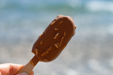 ice cream on a stick on the background of sand and sea with a bokeh effect
