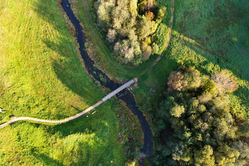 Beautiful colors of autumn. Forest, meadow and river with bridge photographed with a drone on sunny day. Regional park of neris in Lithuania. Dukstai educational trail. Real is beautiful  