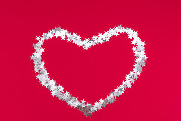 Merry Christmas big heart made of silver stars on a red festive background. Happy new year 2022