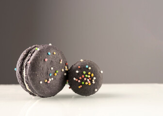 Purple cute french macarons with decorative colorful candies and white cream. Shot isolated against white and gray background