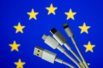 EU flag and different charging cables such as USB, USB-C, Micro USB, lightning cable. Concept for new EU universal charging cable legislation. - obrazy, fototapety, plakaty