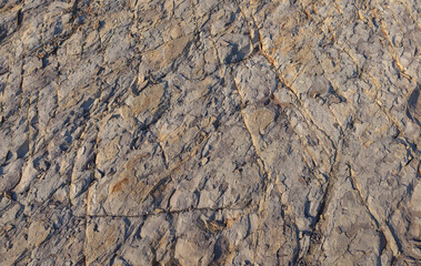 Texture, background layers and cracks in sedimentary rock on cliff face. Rock slate in the mountain. Seamless abstract background. Cracks and layers of sandstone.