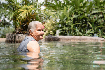 Fototapeta premium hermosa anciana disfrutando del agua en una piscina natural de aguas termales