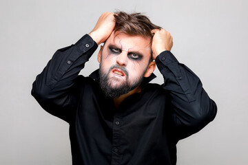 a man with a beard and makeup for Halloween grabbed his hair with his hands