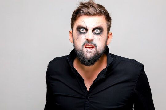 a man with a beard and makeup in the style of the undead on Halloween opened his mouth and shows his teeth